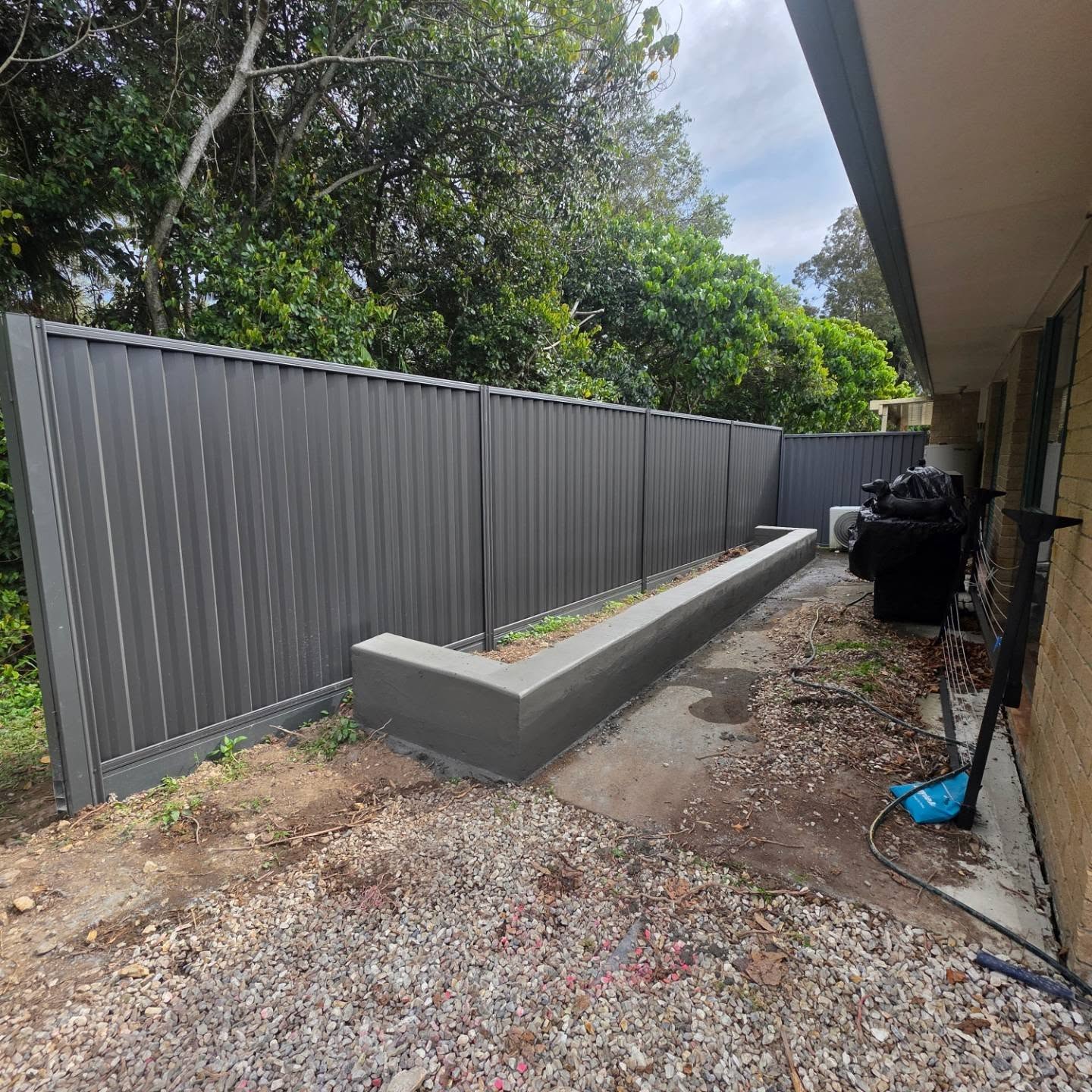 Formed concrete garden bed wall running along the fence line