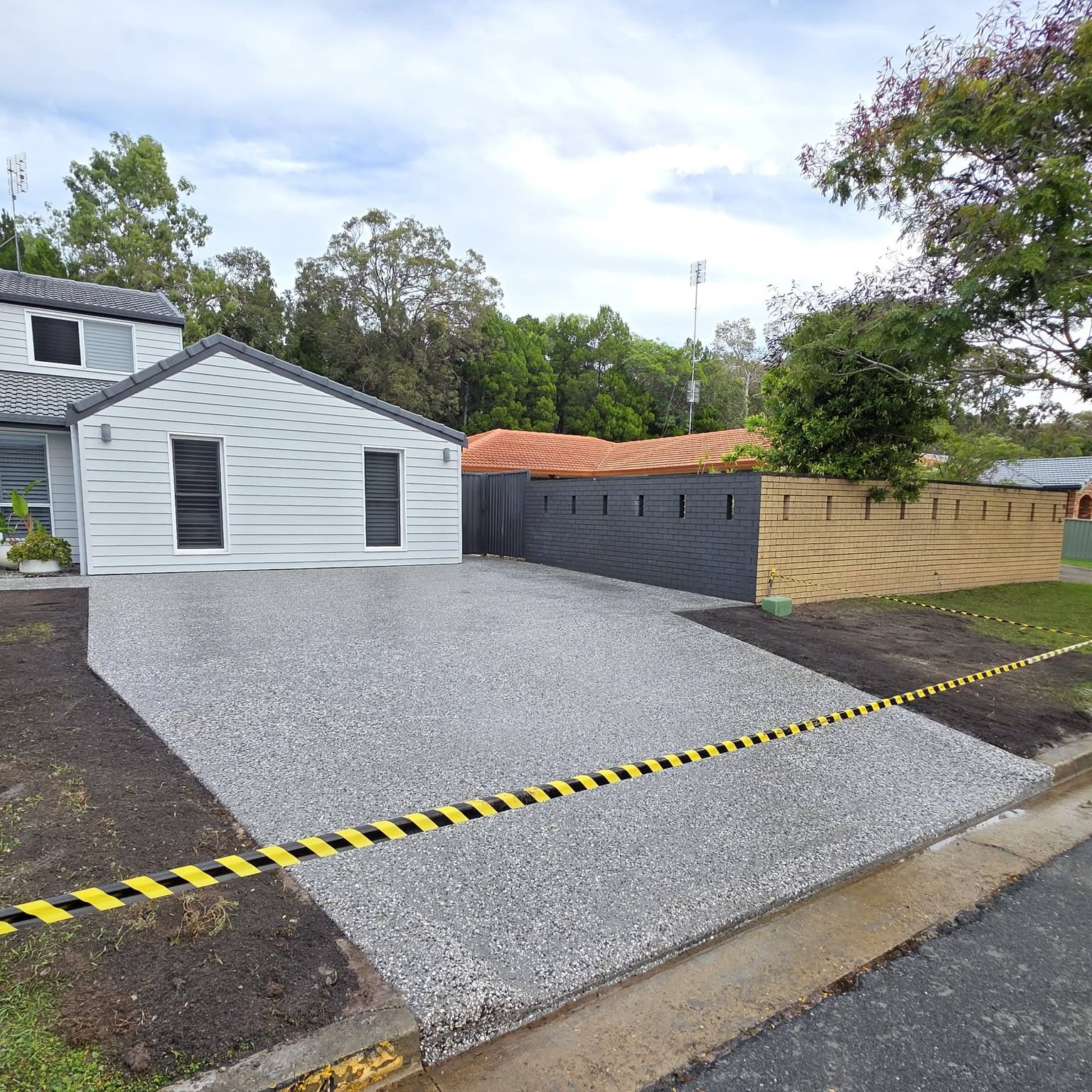 Freshly finished exposed aggregate driveway leading up to a double garage